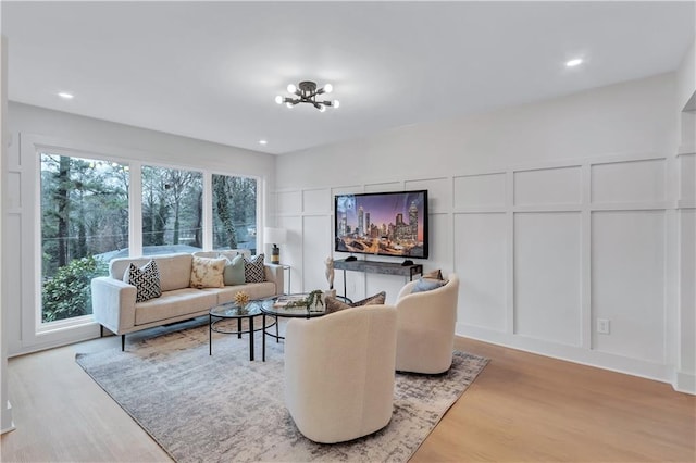 living room featuring a notable chandelier, recessed lighting, wood finished floors, and a decorative wall