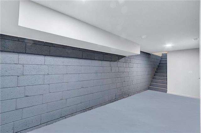 finished below grade area with concrete block wall, visible vents, and stairway