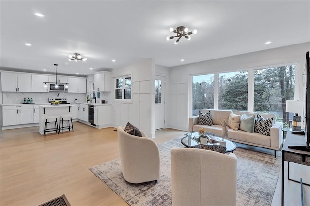 living room with a chandelier, light wood finished floors, and recessed lighting