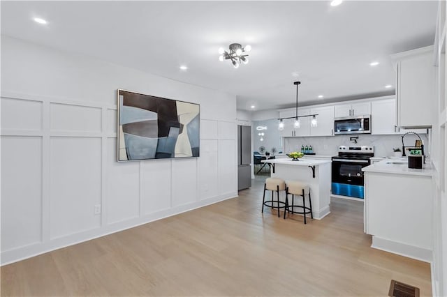 kitchen with a center island, visible vents, a decorative wall, appliances with stainless steel finishes, and a sink