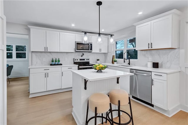 kitchen with a breakfast bar area, appliances with stainless steel finishes, white cabinets, and a sink