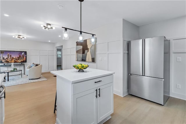 kitchen with light wood-type flooring, freestanding refrigerator, light countertops, and a decorative wall