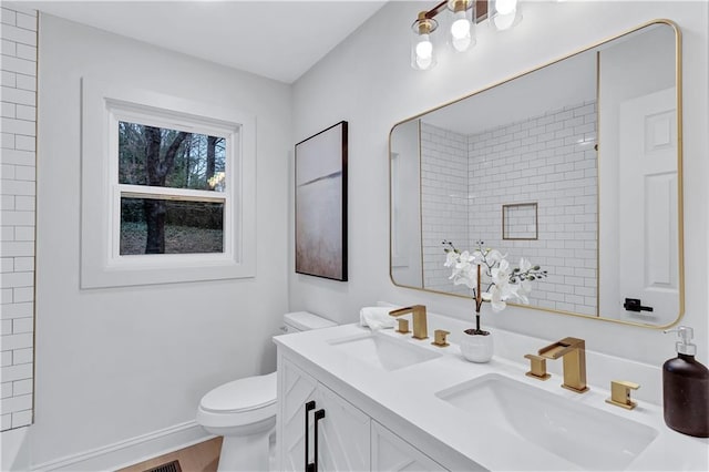 bathroom featuring toilet, double vanity, walk in shower, and a sink