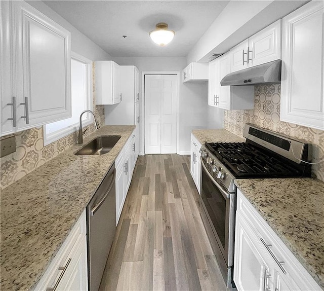 kitchen with backsplash, sink, light stone countertops, appliances with stainless steel finishes, and white cabinets