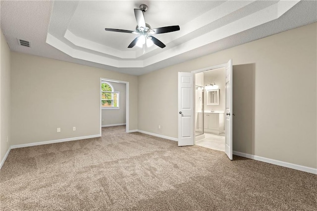 2004 Township Dr, Woodstock, GA 30189 - unfurnished bedroom featuring light carpet, a tray ceiling, connected bathroom, and ceiling fan
