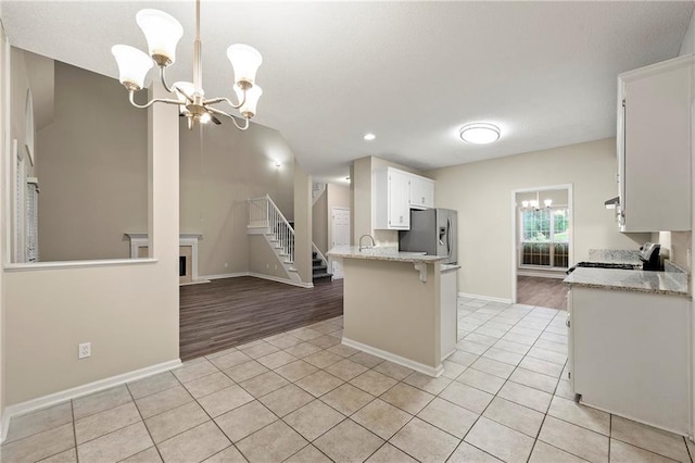 2004 Township Dr, Woodstock, GA 30189 - kitchen featuring a chandelier, stainless steel fridge with ice dispenser, range, light tile patterned floors, and white cabinetry