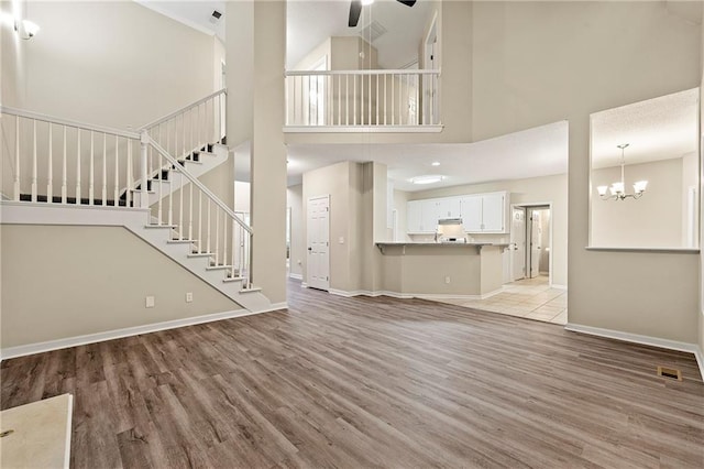2004 Township Dr, Woodstock, GA 30189 - unfurnished living room featuring ceiling fan, light wood-style flooring, a high ceiling, stairway, and a chandelier