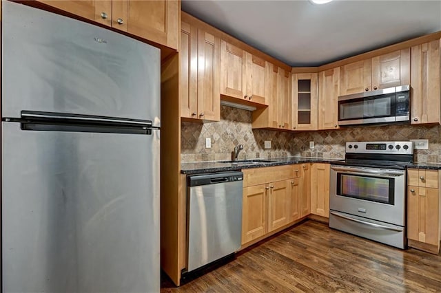 kitchen featuring sink, stainless steel appliances, dark hardwood / wood-style flooring, dark stone counters, and light brown cabinetry