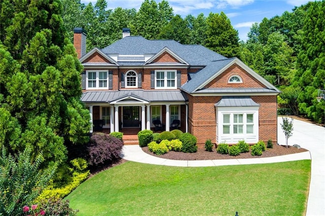 141 Olde Heritage Way, Woodstock, GA 30188 - view of front of property with a standing seam roof, brick siding, a chimney, a front yard, and a porch