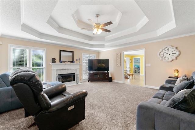 living room featuring baseboards, a raised ceiling, carpet floors, and ornamental molding