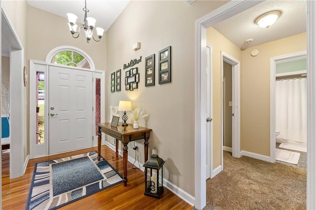 foyer featuring an inviting chandelier, wood finished floors, baseboards, and a textured ceiling