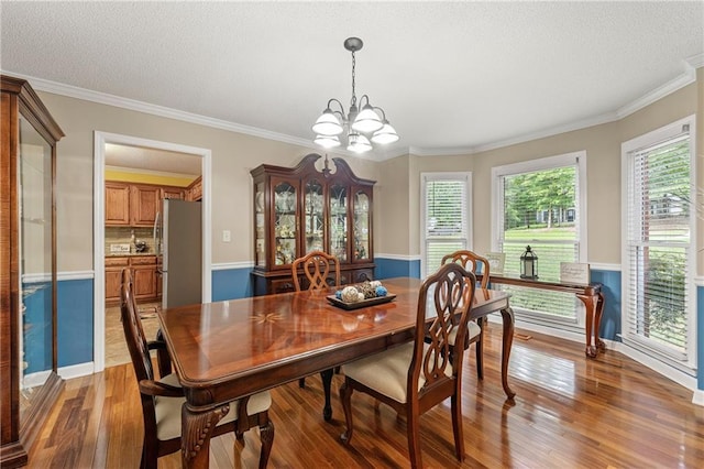 dining room featuring plenty of natural light, a textured ceiling, hardwood / wood-style floors, and ornamental molding