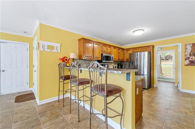 kitchen with a peninsula, crown molding, brown cabinets, and appliances with stainless steel finishes