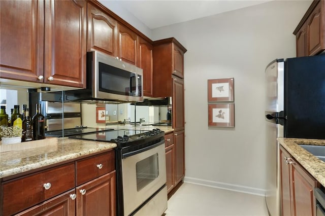kitchen with baseboards, stainless steel appliances, and light stone countertops