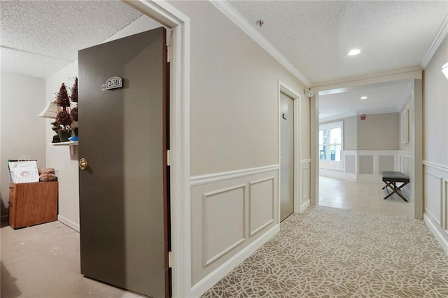 corridor featuring a textured ceiling, ornamental molding, a wainscoted wall, and a decorative wall