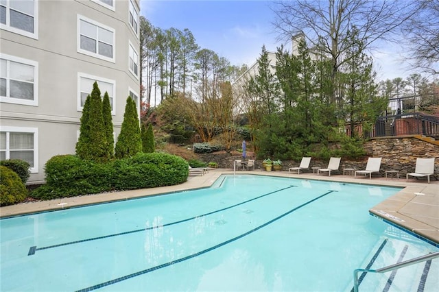 community pool with a patio and fence