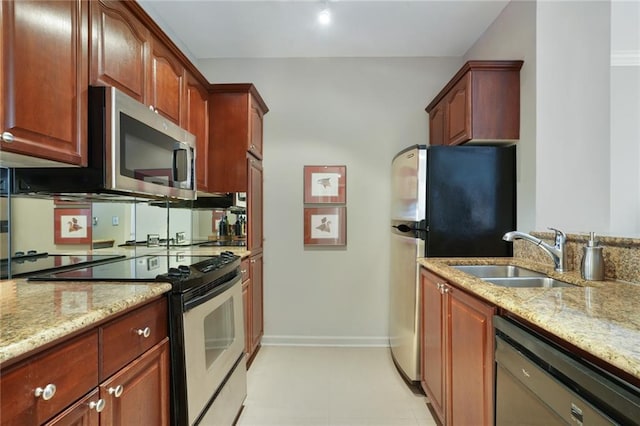 kitchen featuring stainless steel appliances, a sink, baseboards, and light stone countertops
