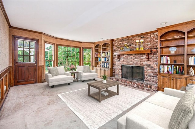 carpeted living area featuring built in features, crown molding, a fireplace, wainscoting, and wood walls
