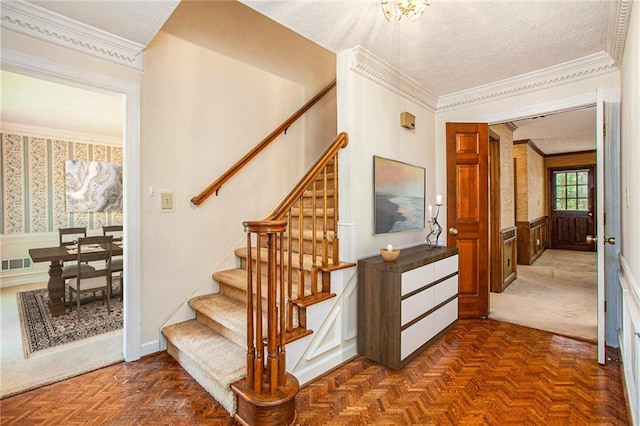 stairs featuring wainscoting, crown molding, and a textured ceiling