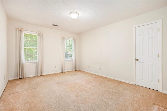 unfurnished room featuring light carpet, baseboards, and a textured ceiling