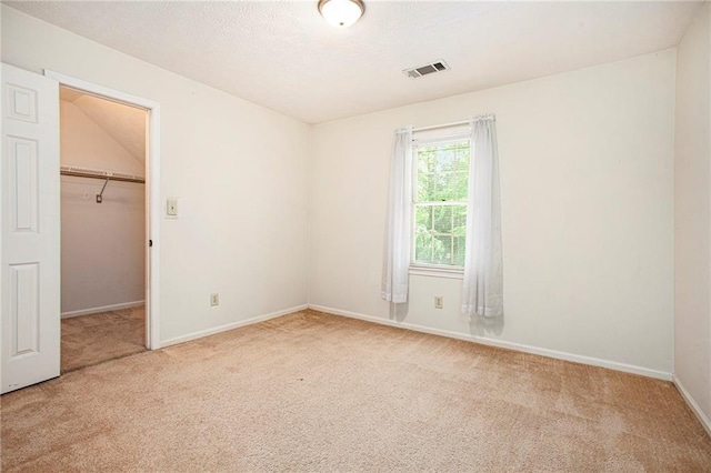 unfurnished bedroom featuring carpet floors, a spacious closet, baseboards, and a closet