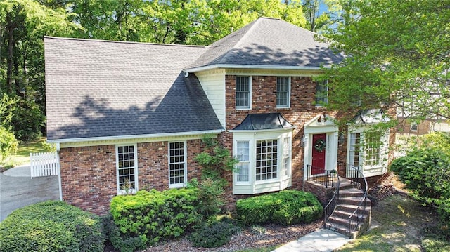view of front of property with roof with shingles and brick siding