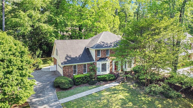 view of front facade with driveway, brick siding, a front yard, a shingled roof, and an attached garage
