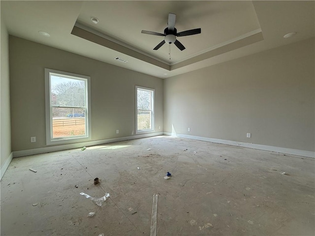 spare room featuring a raised ceiling, visible vents, and baseboards