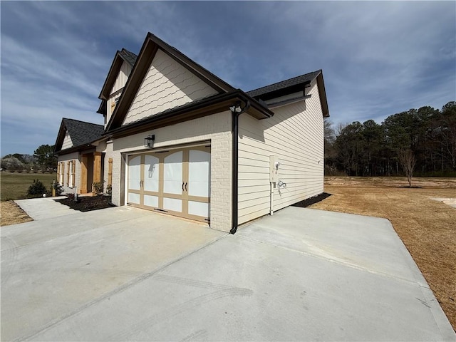 view of side of home featuring a garage, concrete driveway, and brick siding