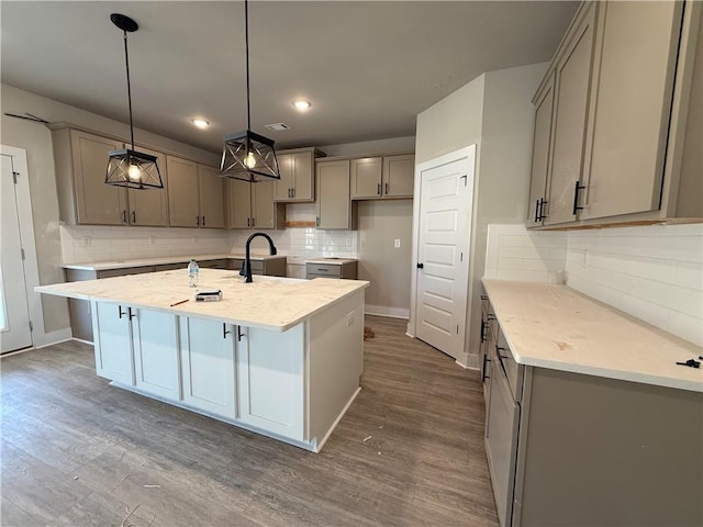 kitchen featuring a kitchen island with sink, baseboards, gray cabinets, and dark wood-style flooring