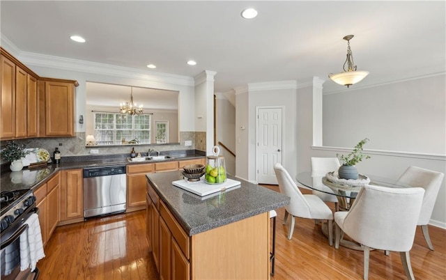 kitchen with gas range, hanging light fixtures, stainless steel dishwasher, a kitchen island, and hardwood / wood-style flooring