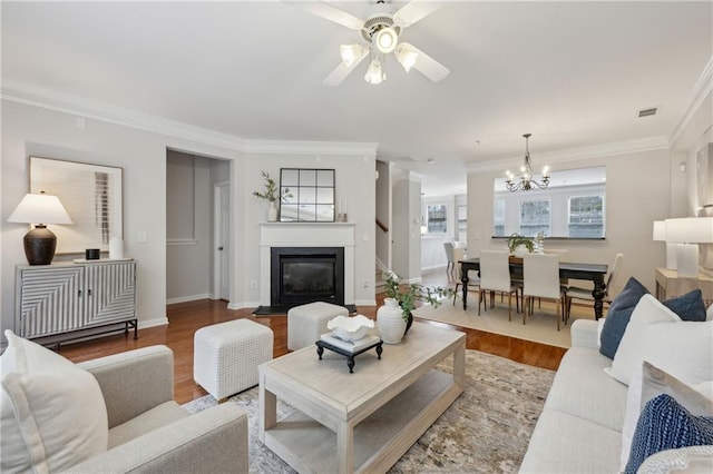 living room featuring ornamental molding, wood-type flooring, and ceiling fan with notable chandelier