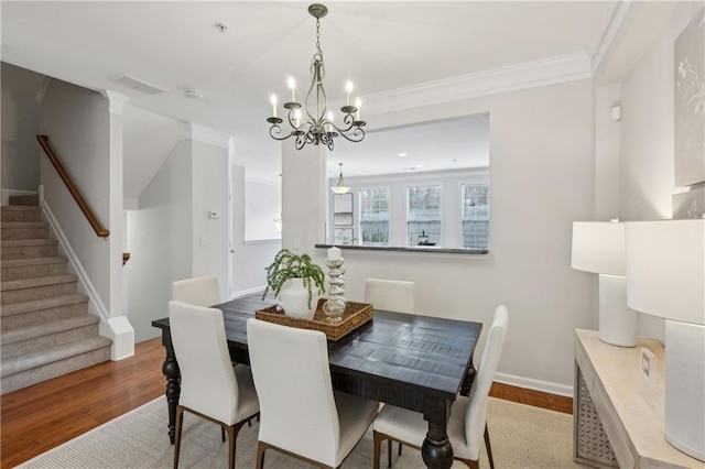 dining room featuring crown molding, light hardwood / wood-style flooring, and a chandelier