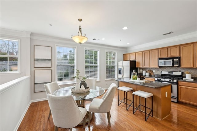 dining area with ornamental molding and light wood-type flooring