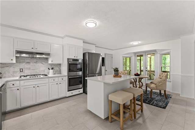 220 Hollyridge Dr, Roswell, GA 30076 - kitchen featuring appliances with stainless steel finishes, under cabinet range hood, french doors, tasteful backsplash, and light countertops