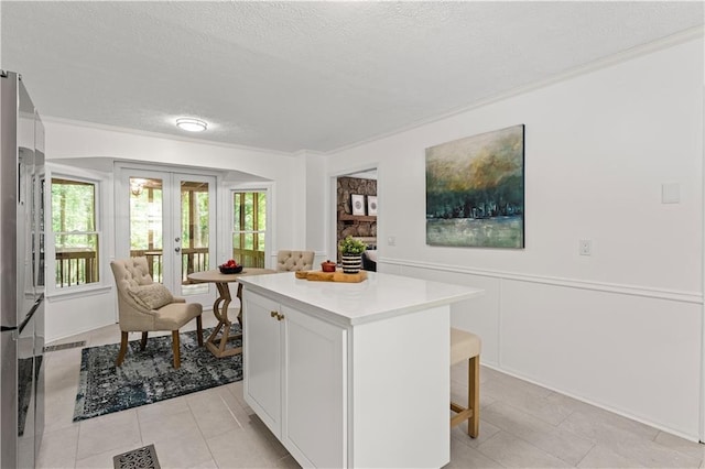 220 Hollyridge Dr, Roswell, GA 30076 - kitchen with freestanding refrigerator, a breakfast bar area, a textured ceiling, light countertops, and white cabinetry