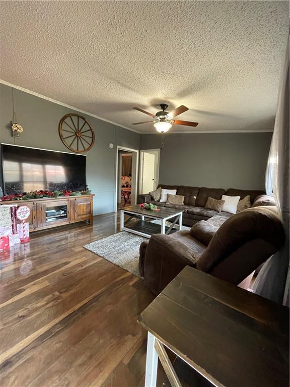 living room with hardwood / wood-style floors, a textured ceiling, ceiling fan, and crown molding