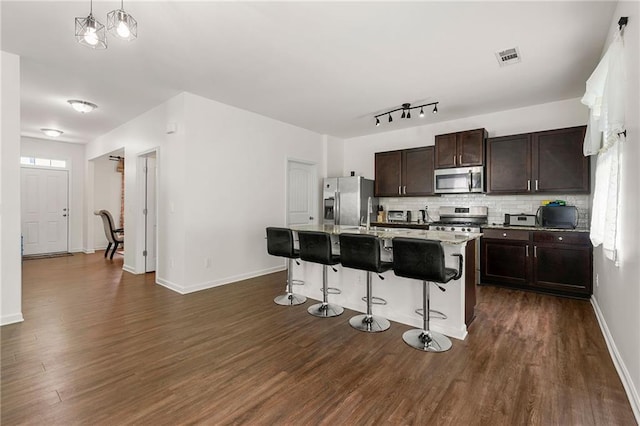 105 Arbor Creek Trl, Dallas, GA 30157 - kitchen with appliances with stainless steel finishes, dark wood-style floors, tasteful backsplash, a kitchen bar, and dark brown cabinetry