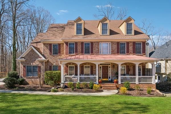 view of front of home with brick siding, a porch, and a front yard