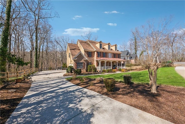 view of front of house with covered porch, a front lawn, and fence