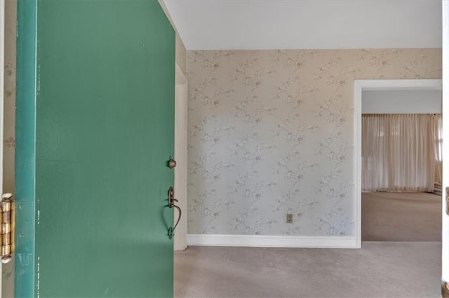 spare room with wallpapered walls, carpet, and baseboards