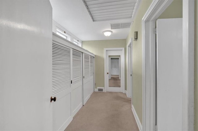 hall featuring visible vents, light colored carpet, and baseboards