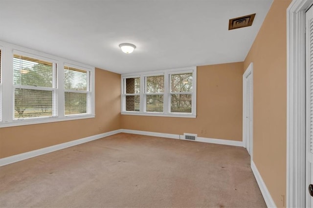 unfurnished room with visible vents, light colored carpet, and baseboards