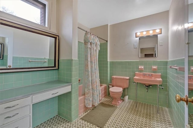 bathroom featuring shower / bath combo, tile patterned flooring, wainscoting, tile walls, and toilet