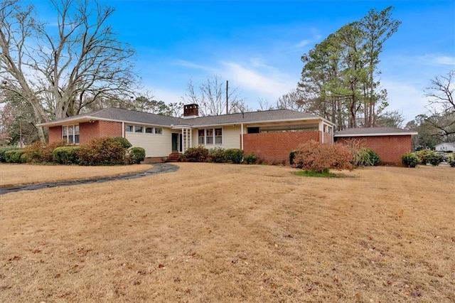 single story home featuring brick siding, a chimney, and a front lawn