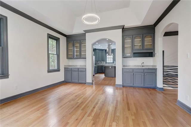 kitchen with sink, a raised ceiling, light wood-type flooring, and gray cabinets