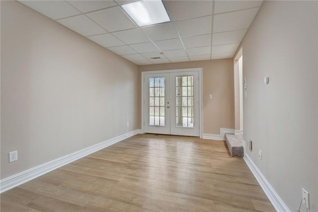 unfurnished room with a paneled ceiling, french doors, and light hardwood / wood-style floors