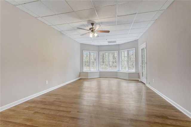 spare room with ceiling fan, a paneled ceiling, and wood-type flooring