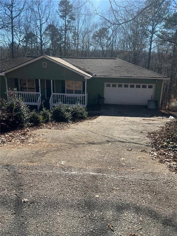 view of front facade with driveway, a garage, central AC unit, roof with shingles, and a porch