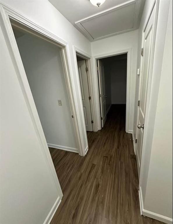 hallway featuring dark wood-style flooring and baseboards